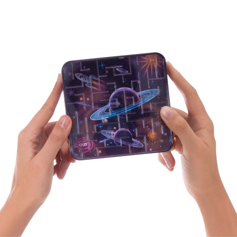 Hands holding a square maze game with a colorful outer space design featuring planets, stars, and rockets.